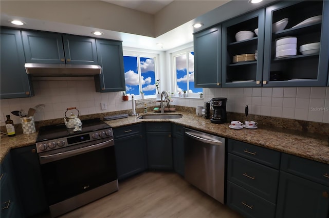 kitchen with dark stone counters, sink, stainless steel appliances, and light hardwood / wood-style flooring