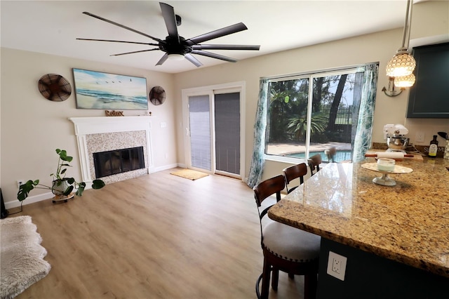 living room with light hardwood / wood-style flooring, ceiling fan, and a tiled fireplace