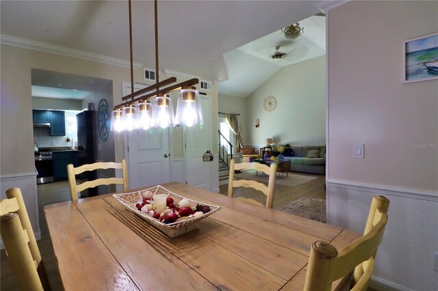 dining space with crown molding, a healthy amount of sunlight, lofted ceiling, and hardwood / wood-style flooring