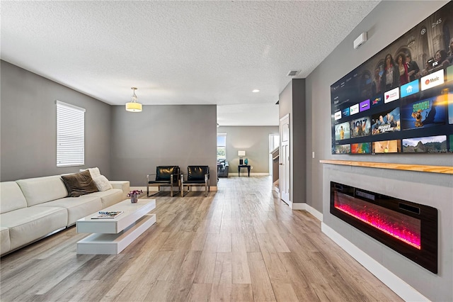 living room featuring a textured ceiling, light hardwood / wood-style flooring, and a healthy amount of sunlight