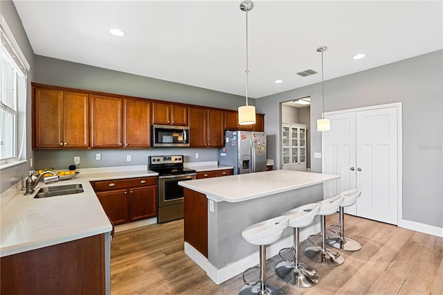 kitchen featuring sink, a center island, light hardwood / wood-style flooring, stainless steel appliances, and pendant lighting