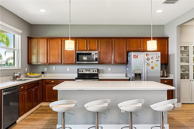 kitchen featuring stainless steel appliances, light hardwood / wood-style flooring, and pendant lighting