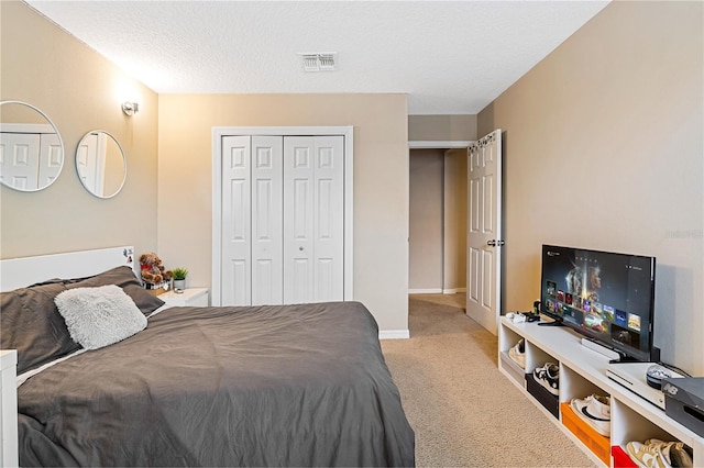 bedroom featuring a textured ceiling, a closet, and light colored carpet