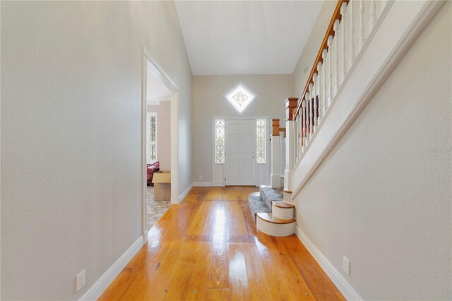 entryway featuring a towering ceiling and light wood-type flooring