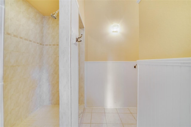 full bath with a wainscoted wall, tile patterned flooring, and tiled shower