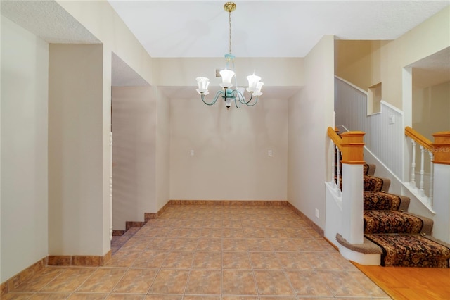 spare room with a chandelier, baseboards, and stairs