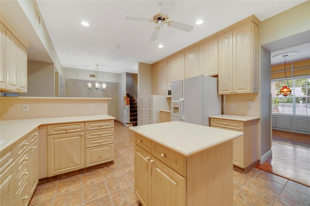 kitchen with white appliances, light brown cabinetry, light countertops, and decorative light fixtures