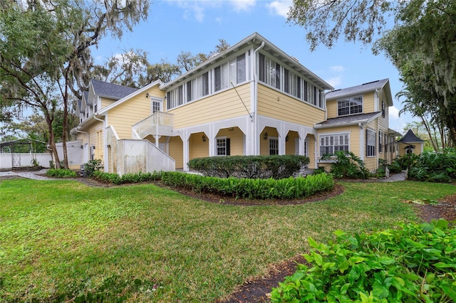 view of front facade with a sunroom, fence, and a front yard