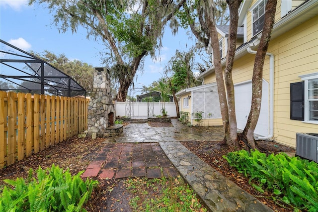 view of yard featuring a lanai, a fenced backyard, a patio, and central AC unit