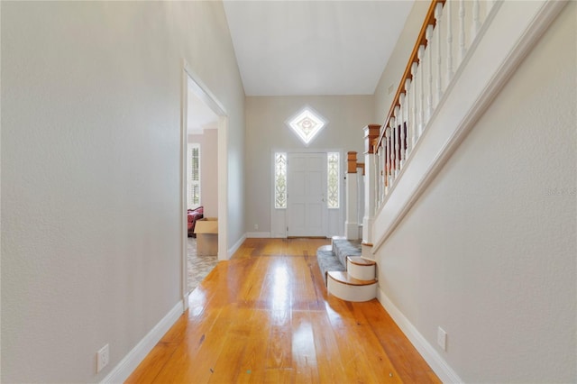 entryway with baseboards, stairway, and light wood finished floors