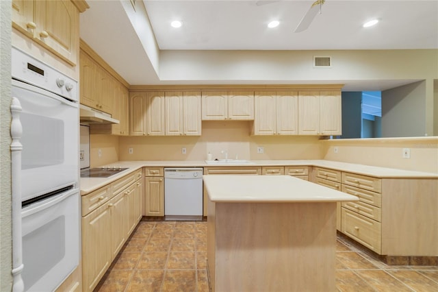 kitchen with under cabinet range hood, white appliances, a kitchen island, light countertops, and light brown cabinetry