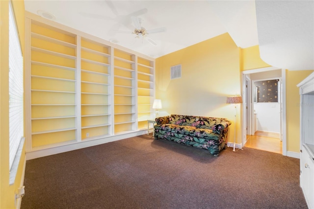 living area featuring ceiling fan, built in shelves, carpet flooring, and visible vents