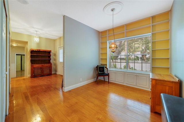 living area with built in shelves, baseboards, and wood finished floors