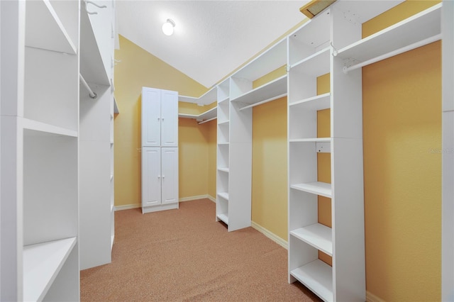 walk in closet with lofted ceiling and light colored carpet