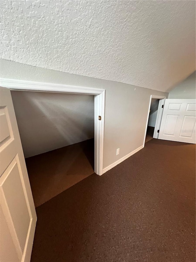 bonus room featuring vaulted ceiling, a textured ceiling, and baseboards