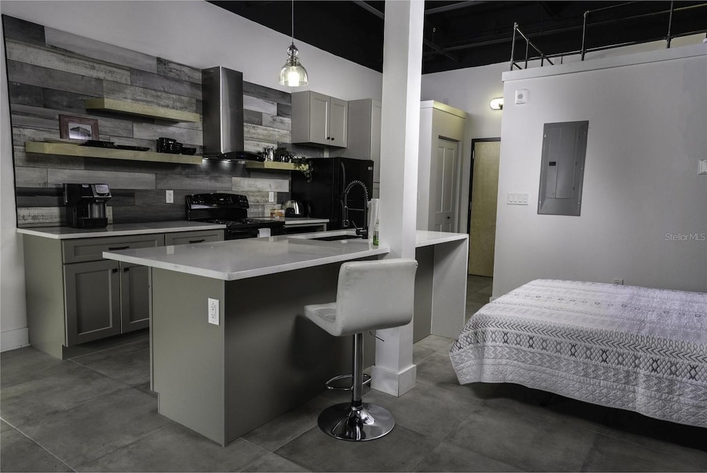 kitchen featuring black appliances, decorative backsplash, wall chimney range hood, a kitchen bar, and decorative light fixtures