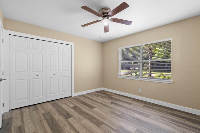 unfurnished bedroom featuring ceiling fan, hardwood / wood-style floors, and a closet