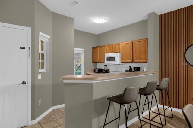 kitchen with light tile patterned flooring, a kitchen bar, and kitchen peninsula