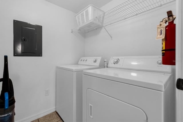 laundry area featuring light tile patterned floors, electric panel, and washing machine and clothes dryer