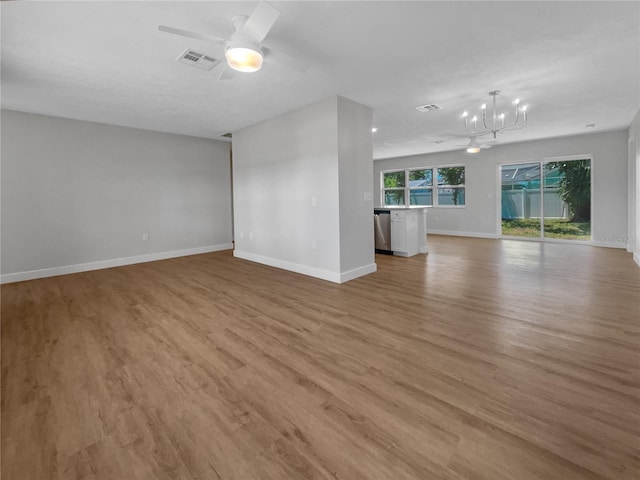 unfurnished living room with ceiling fan with notable chandelier and light hardwood / wood-style floors