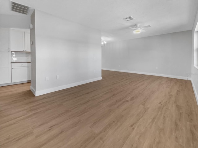 unfurnished room with light wood-type flooring, baseboards, visible vents, and a ceiling fan