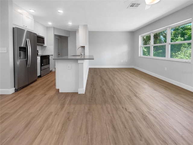 kitchen featuring visible vents, white cabinets, appliances with stainless steel finishes, open floor plan, and a sink