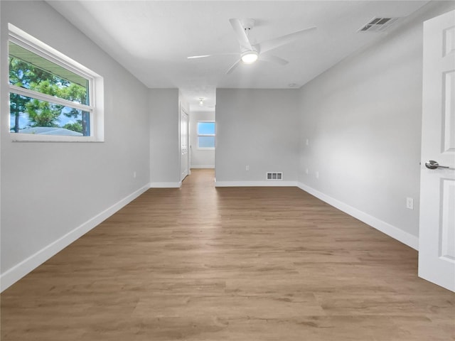 empty room with ceiling fan, light wood-type flooring, and a wealth of natural light