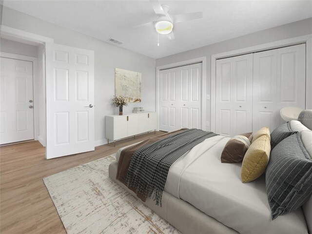 bedroom featuring ceiling fan, light wood-type flooring, and two closets