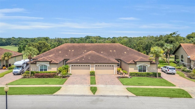 mediterranean / spanish home with a front yard, driveway, a tiled roof, and stucco siding