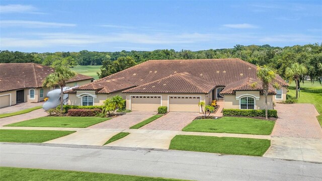 mediterranean / spanish home with a front lawn and a garage