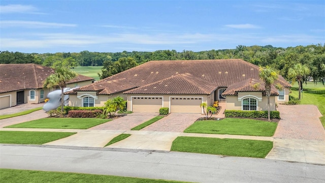 view of front facade featuring stucco siding, a front yard, decorative driveway, and a tiled roof