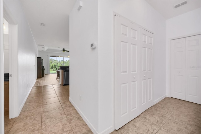 hallway with light tile patterned floors, baseboards, and visible vents