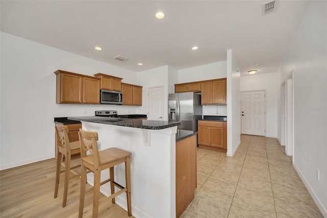 kitchen featuring visible vents, a kitchen island, appliances with stainless steel finishes, and brown cabinetry