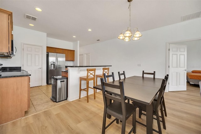 dining room with light wood-type flooring and an inviting chandelier