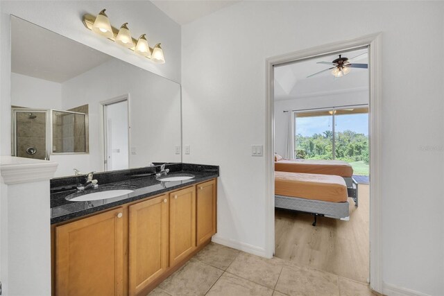 bathroom featuring ceiling fan, a shower with door, dual vanity, and tile patterned flooring