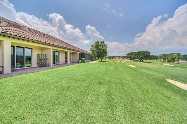 view of yard with view of golf course, a patio, and central AC unit