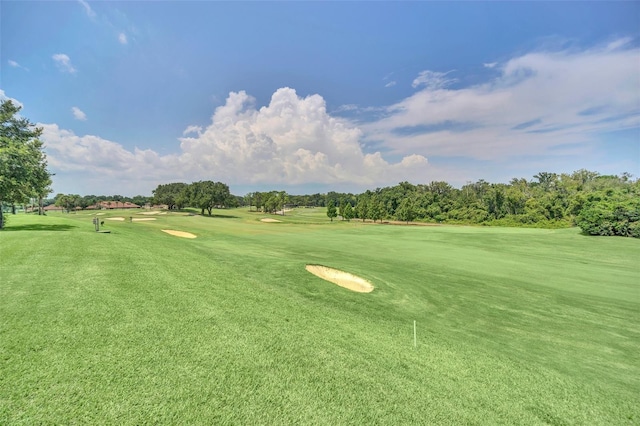 view of property's community with view of golf course and a yard