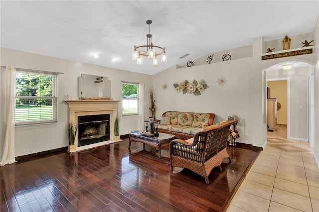 tiled living room with vaulted ceiling, a wealth of natural light, and an inviting chandelier