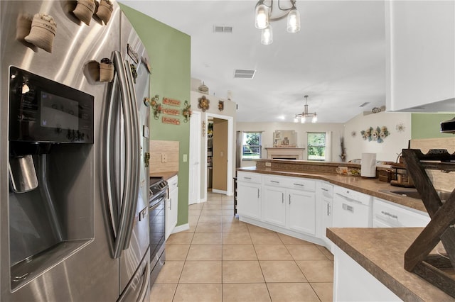 kitchen with white cabinets, light tile patterned flooring, stainless steel appliances, and a chandelier