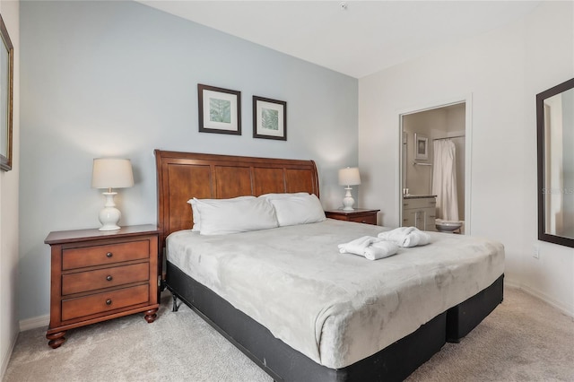 bedroom featuring light colored carpet and ensuite bath