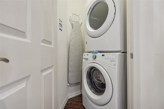 clothes washing area featuring dark wood-type flooring and stacked washer and clothes dryer