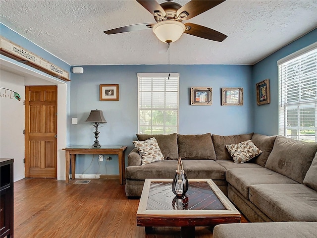 living room featuring wood-type flooring, ceiling fan, and a textured ceiling