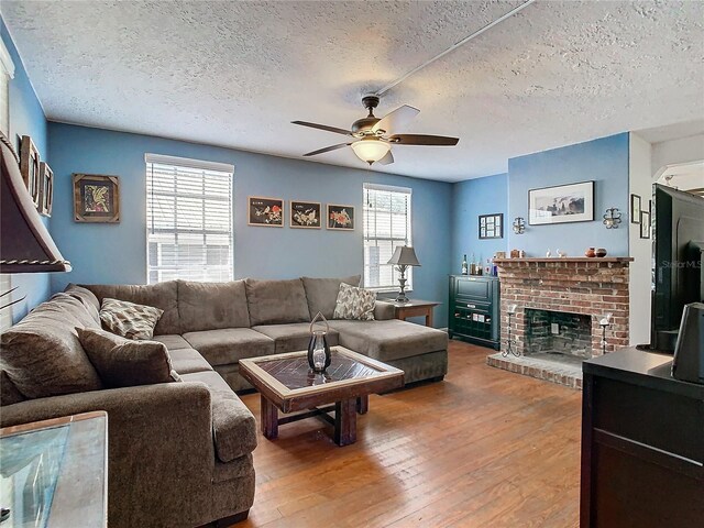 living room with a healthy amount of sunlight, a fireplace, ceiling fan, and hardwood / wood-style flooring