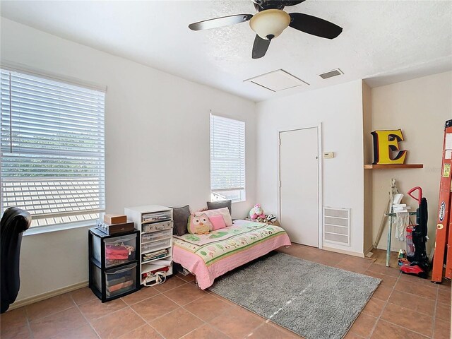 bedroom with light tile patterned floors, multiple windows, ceiling fan, and a textured ceiling