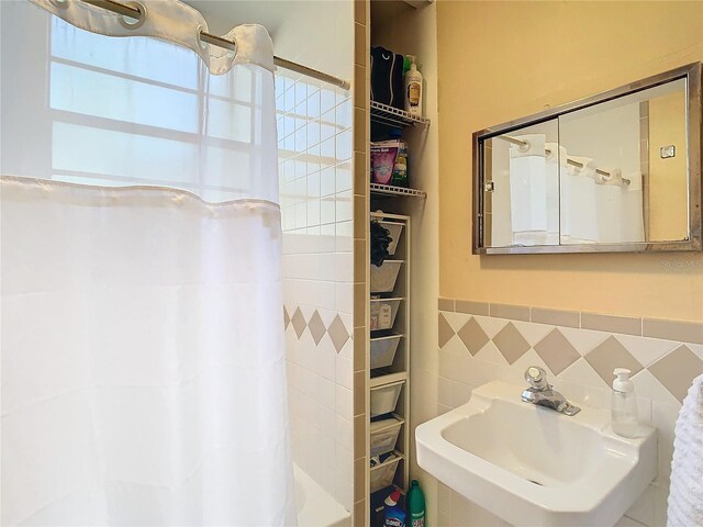 bathroom with curtained shower, tile walls, and sink