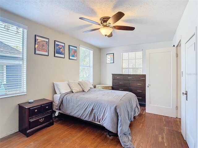 bedroom featuring a textured ceiling, wood-type flooring, and ceiling fan