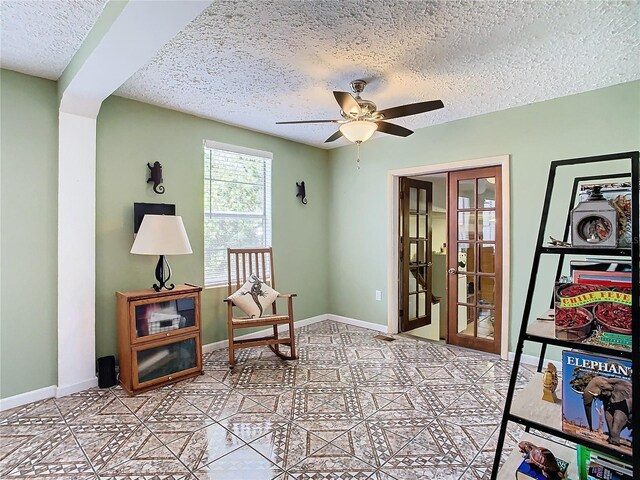 sitting room with a textured ceiling, light tile patterned floors, ceiling fan, and french doors