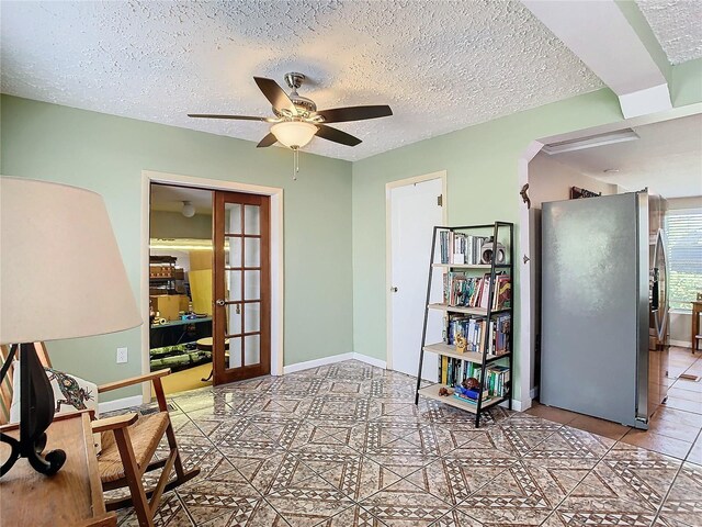 interior space with light tile patterned floors, ceiling fan, french doors, and a textured ceiling