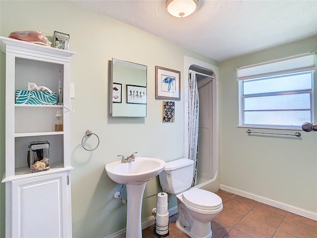 bathroom with tile patterned flooring, walk in shower, and toilet