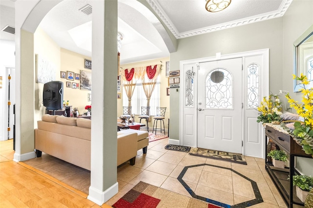 entryway featuring light hardwood / wood-style flooring, a raised ceiling, and ornamental molding